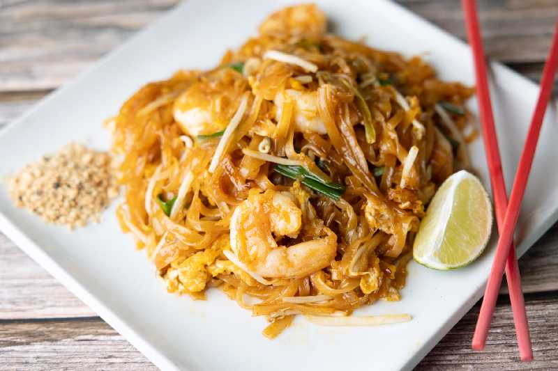 A plate of Pad Thai with shrimp, garnished with lime and crushed peanuts, showcasing a classic dish from Thai Boran Restaurant, La Orilla Road Northwest, Albuquerque, NM, perfect for those searching for Thai food near me.