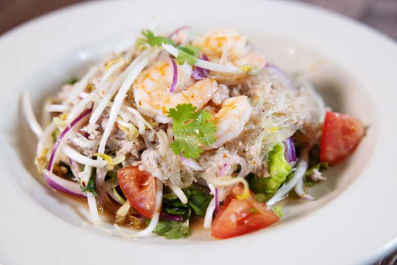 A refreshing glass noodle salad with shrimp, vegetables, and cilantro, representing the light yet flavorful options of Thai food at this Thai restaurant near me.