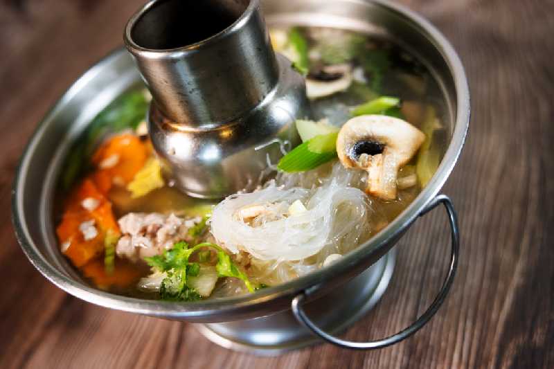 A traditional hot pot filled with flavorful broth, vegetables, and noodles, highlighting authentic Thai cuisine at Thai Boran for anyone seeking Thai restaurants near me.